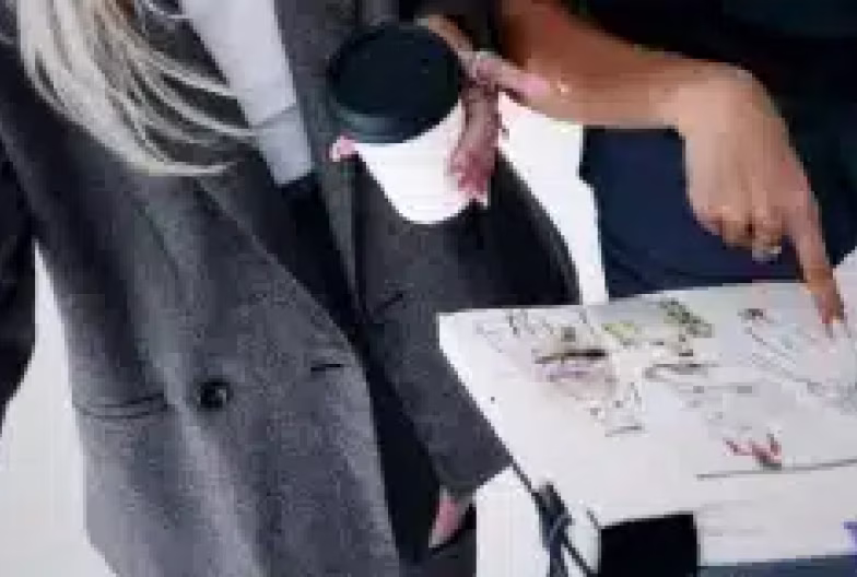 Two people discussing a document, one holding coffee and the other pointing at the paper.