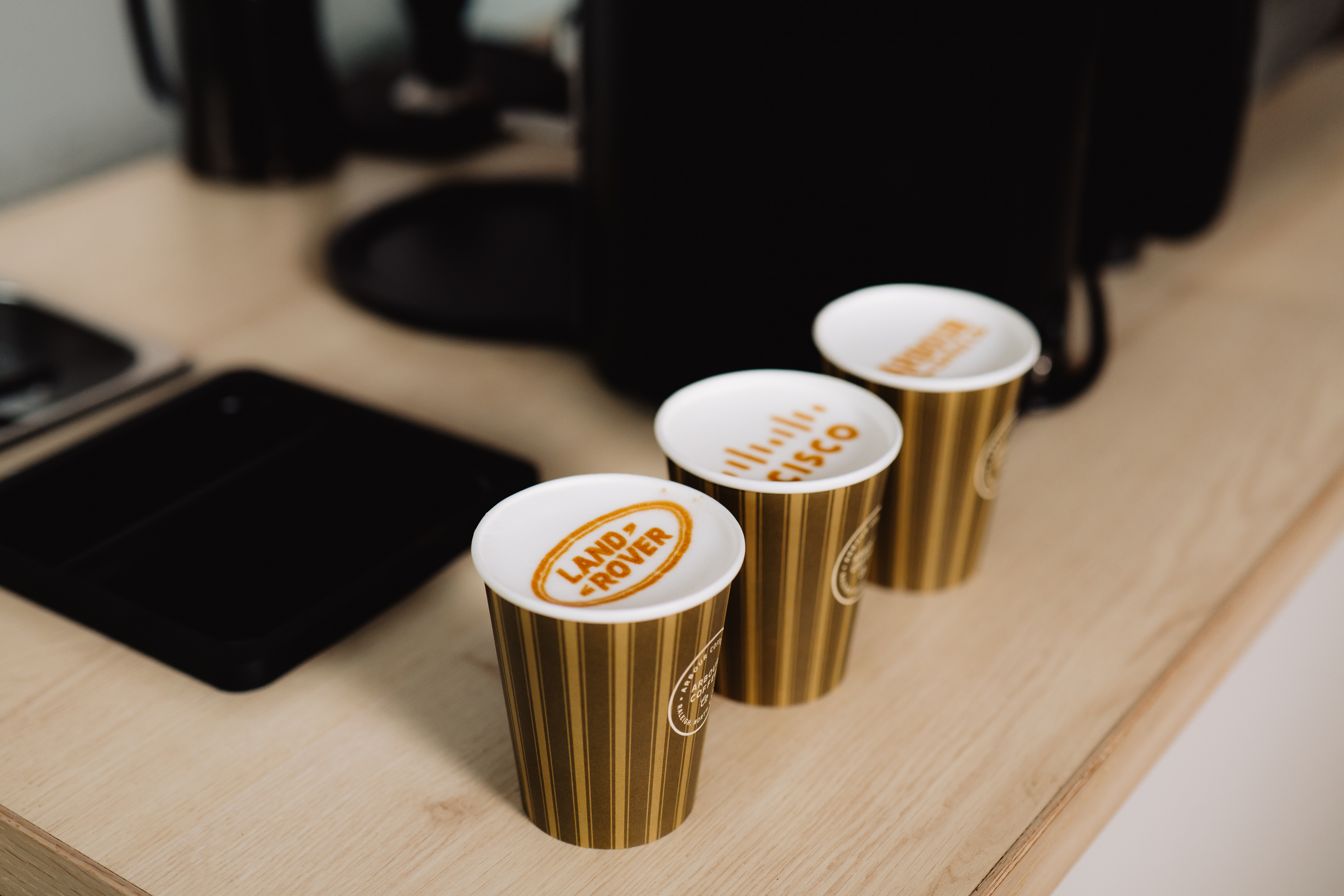 Gold branded coffee cups with logo lids at a corporate event