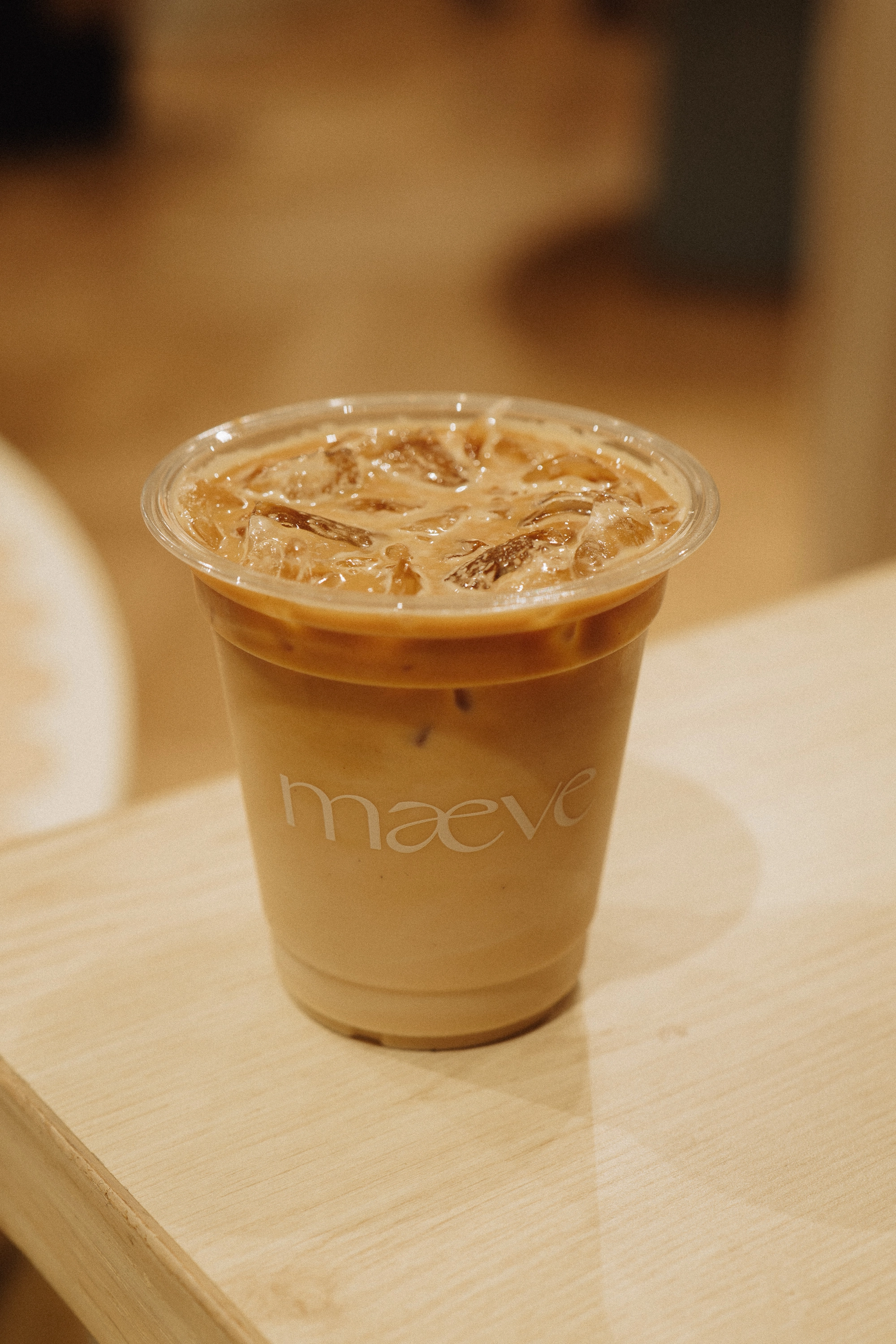 Iced latte in a Maeve-branded cup at a boutique pop-up
