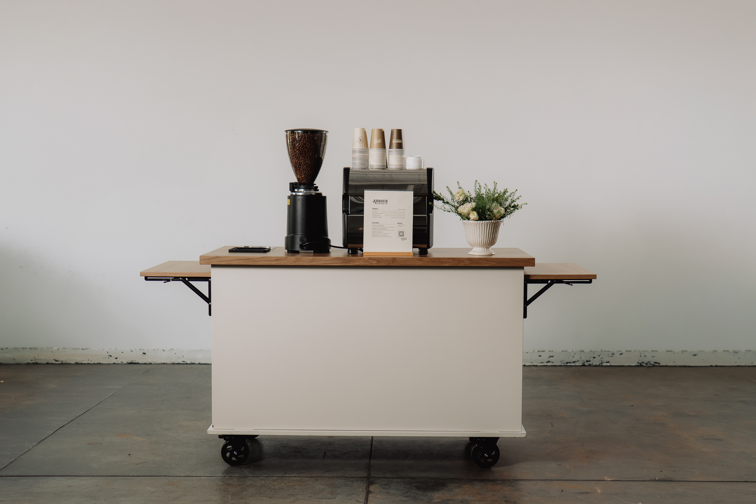 Arbour's white catering espresso cart styled with a menu and flowers