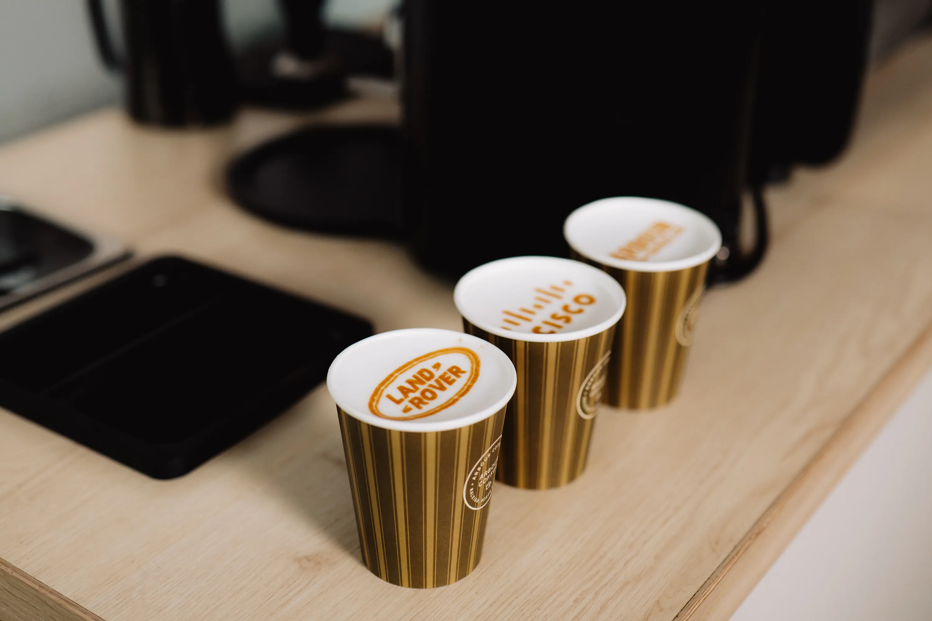 Gold branded coffee cups with logo lids at a corporate event