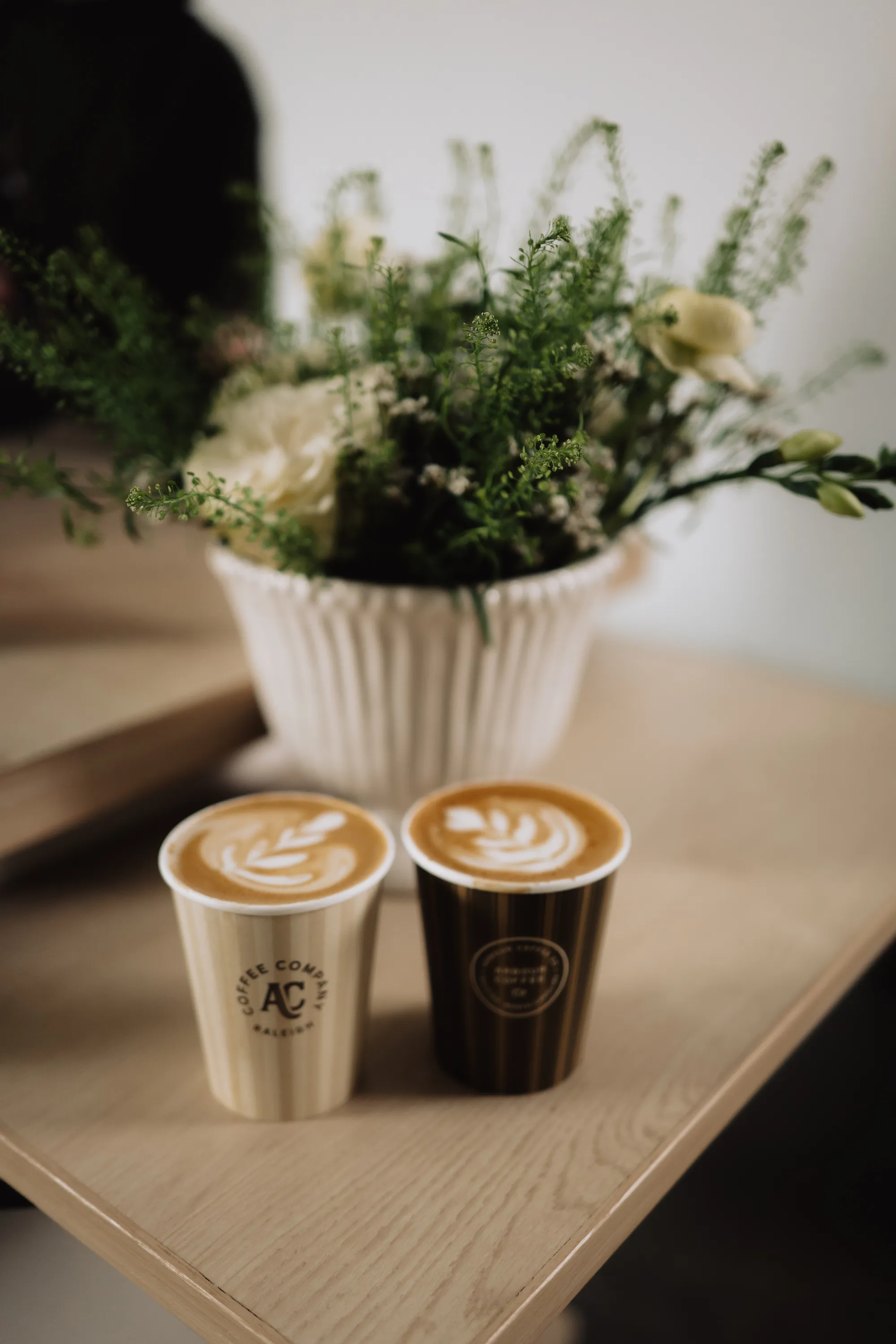 Two latte art coffees styled with wedding florals
