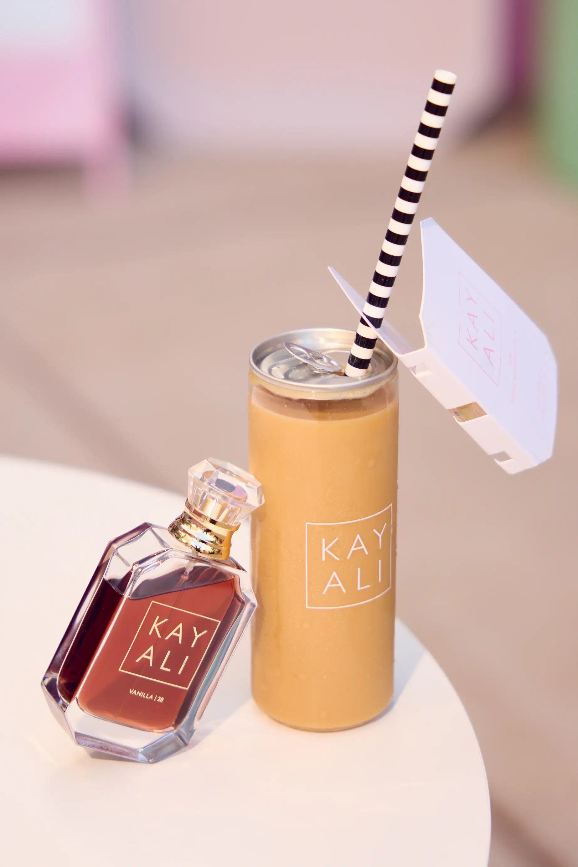 Kayali Vanilla 28 perfume beside a matching Kayali-branded canned latte.