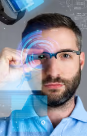 Homme portant des lunettes regardant un écran futuriste avec des données holographiques bleues.