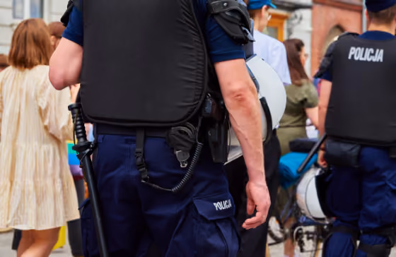 Des policiers en uniforme bleu avec gilets pare-balles surveillent une foule en plein air.