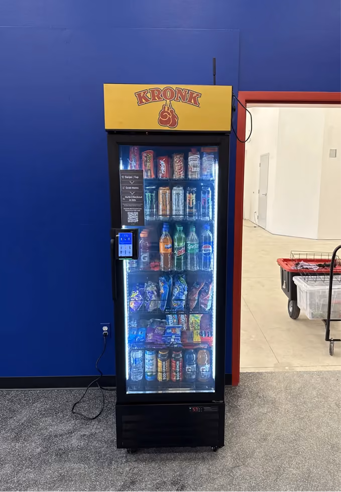 Kronk vending machine stocked with drinks and snacks, featuring digital payment and QR code.