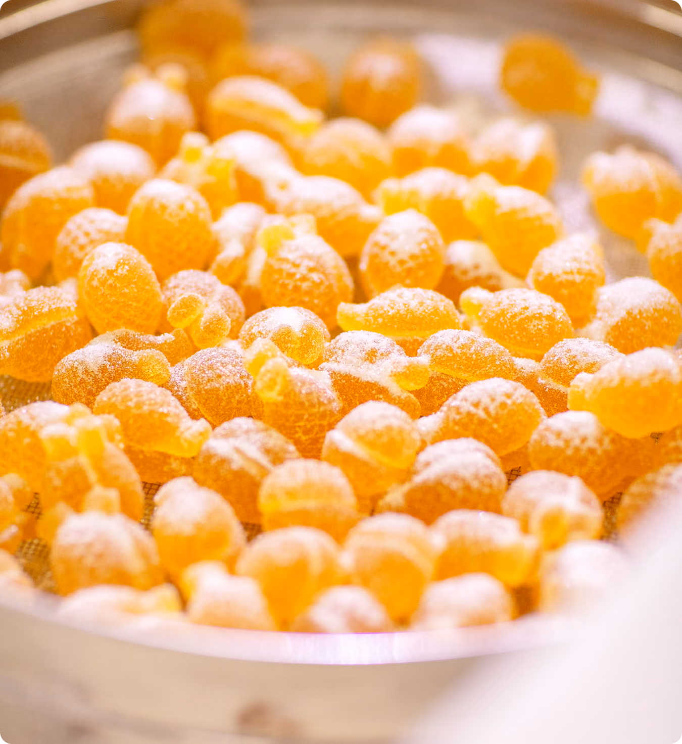 Oranje pâte de fruits-snoepjes op een zeef, bestoven met suiker