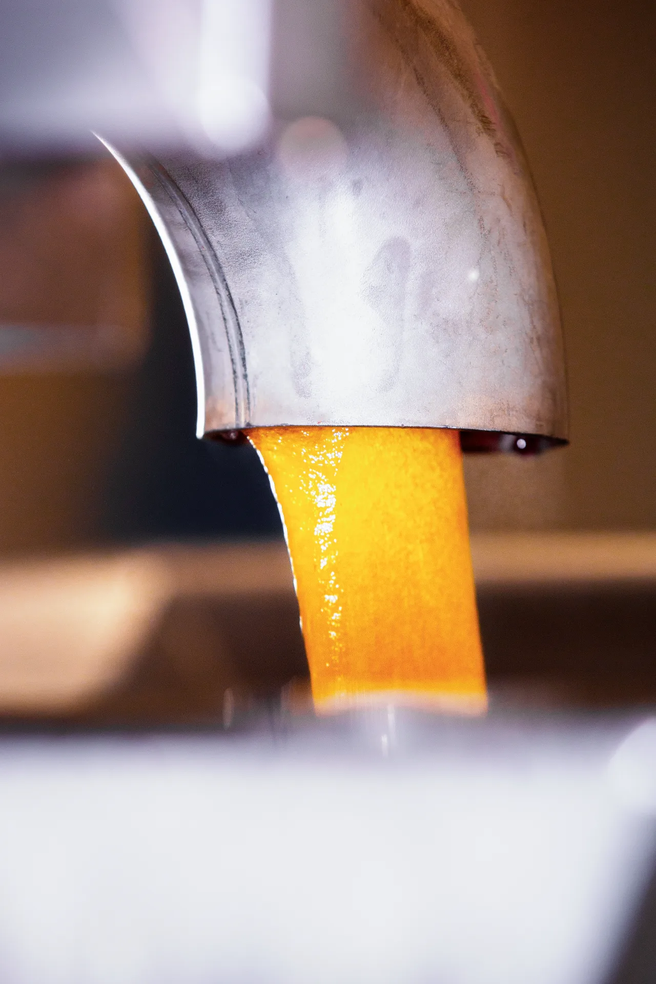 Oranje pâte de fruits-massa die uit een gietkop stroomt in de productiehal