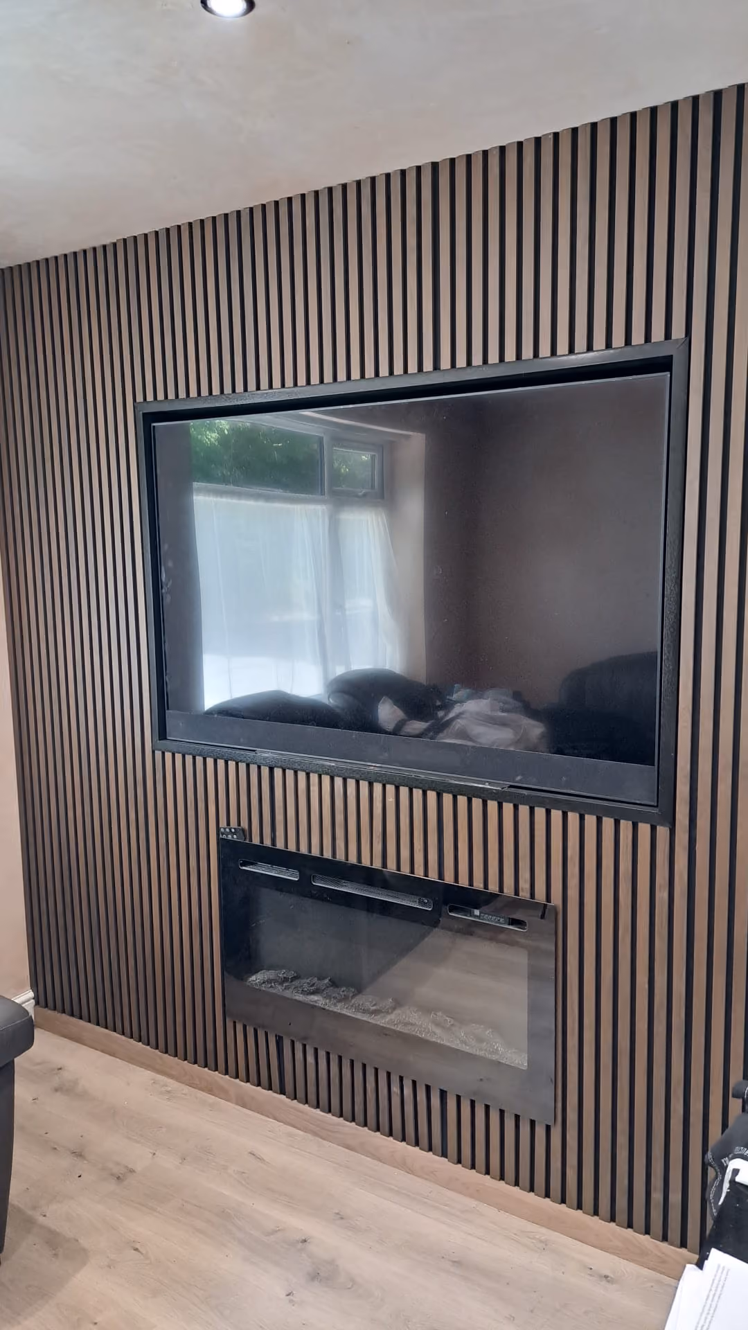 Bespoke oak slatted media wall with recessed TV and electric fire, made and fitted in Ormskirk.
