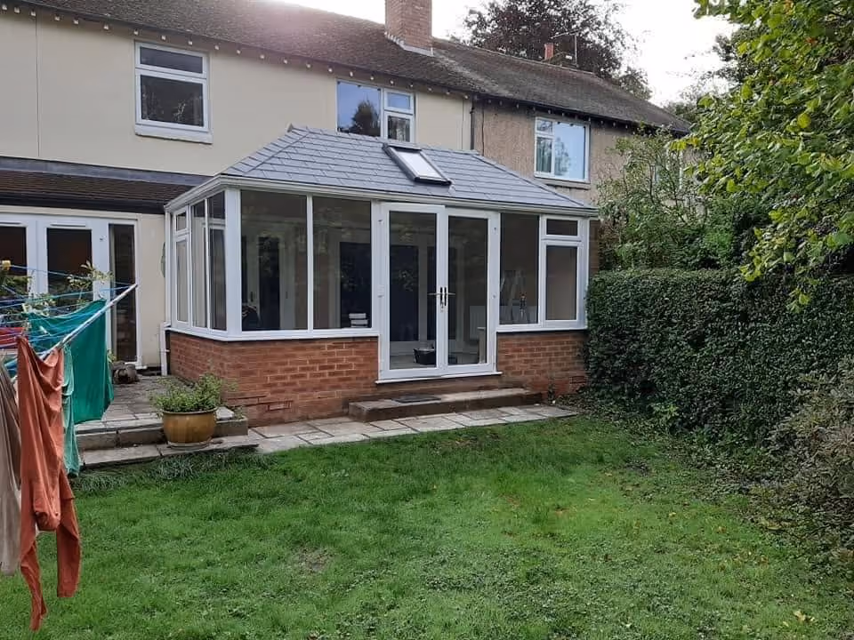 Conservatory with insulated tiled warm roof, roof window and white uPVC french doors on a brick base near Ormskirk