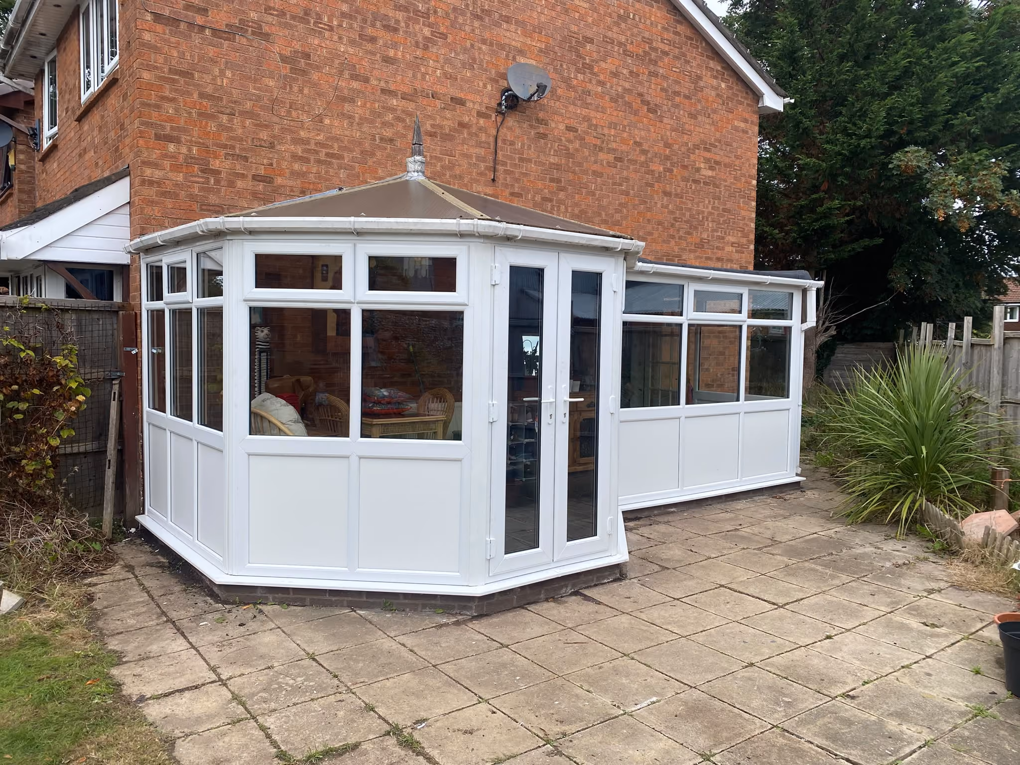 White uPVC Victorian-style conservatory with French doors and a solid roof on a paved patio near Ormskirk