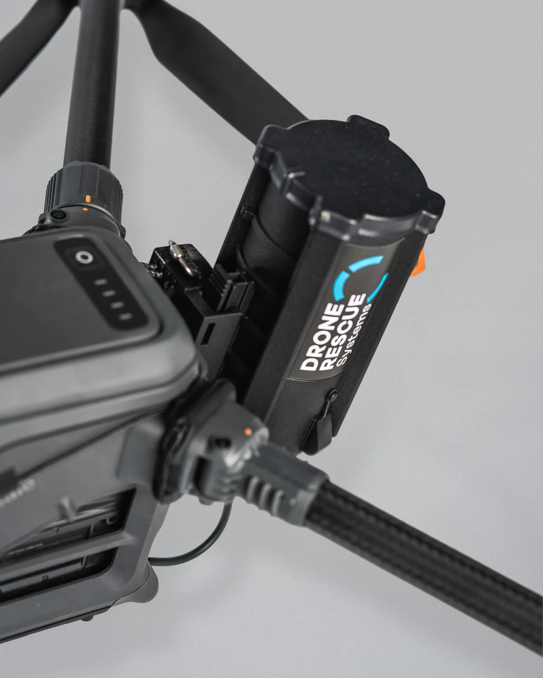 Close-up of drone arm and attached black rectangular Drone Rescue Systems device.