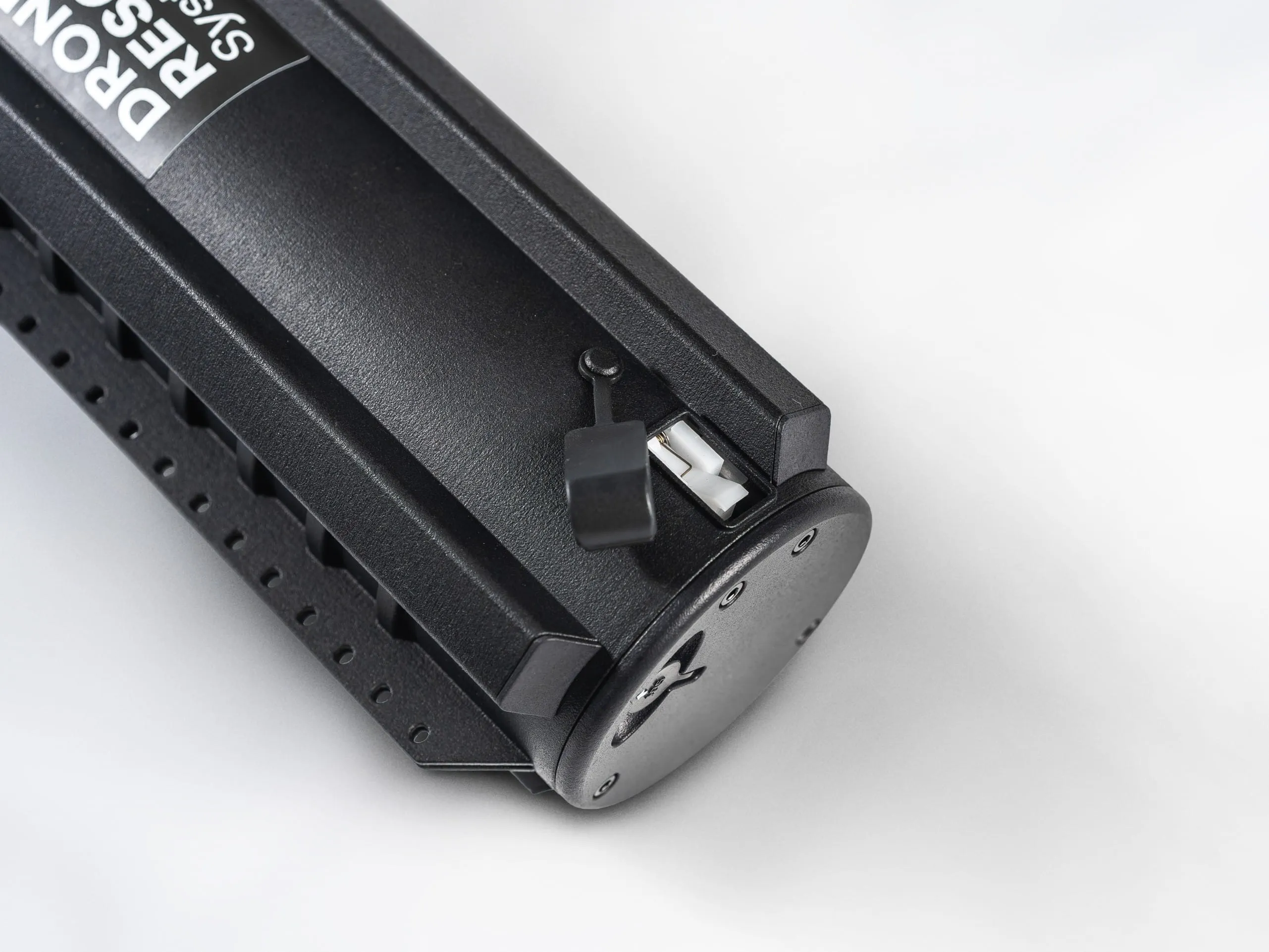 Close-up of a black drone rescue system battery with a small covered port on top.
