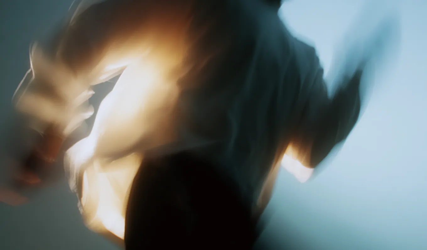 Blurred abstract image of a person in motion with light and shadow effects.