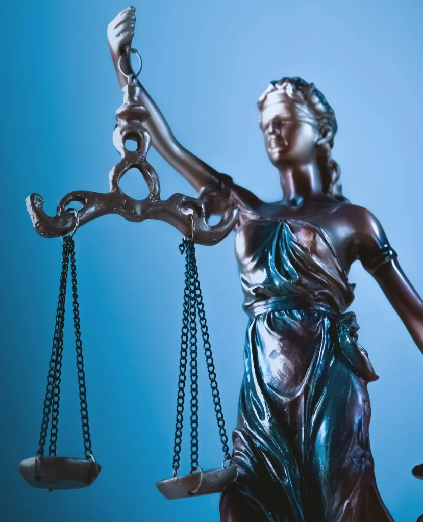 Lady Justice statue with scales against a blue background representing criminal defense in Missoula