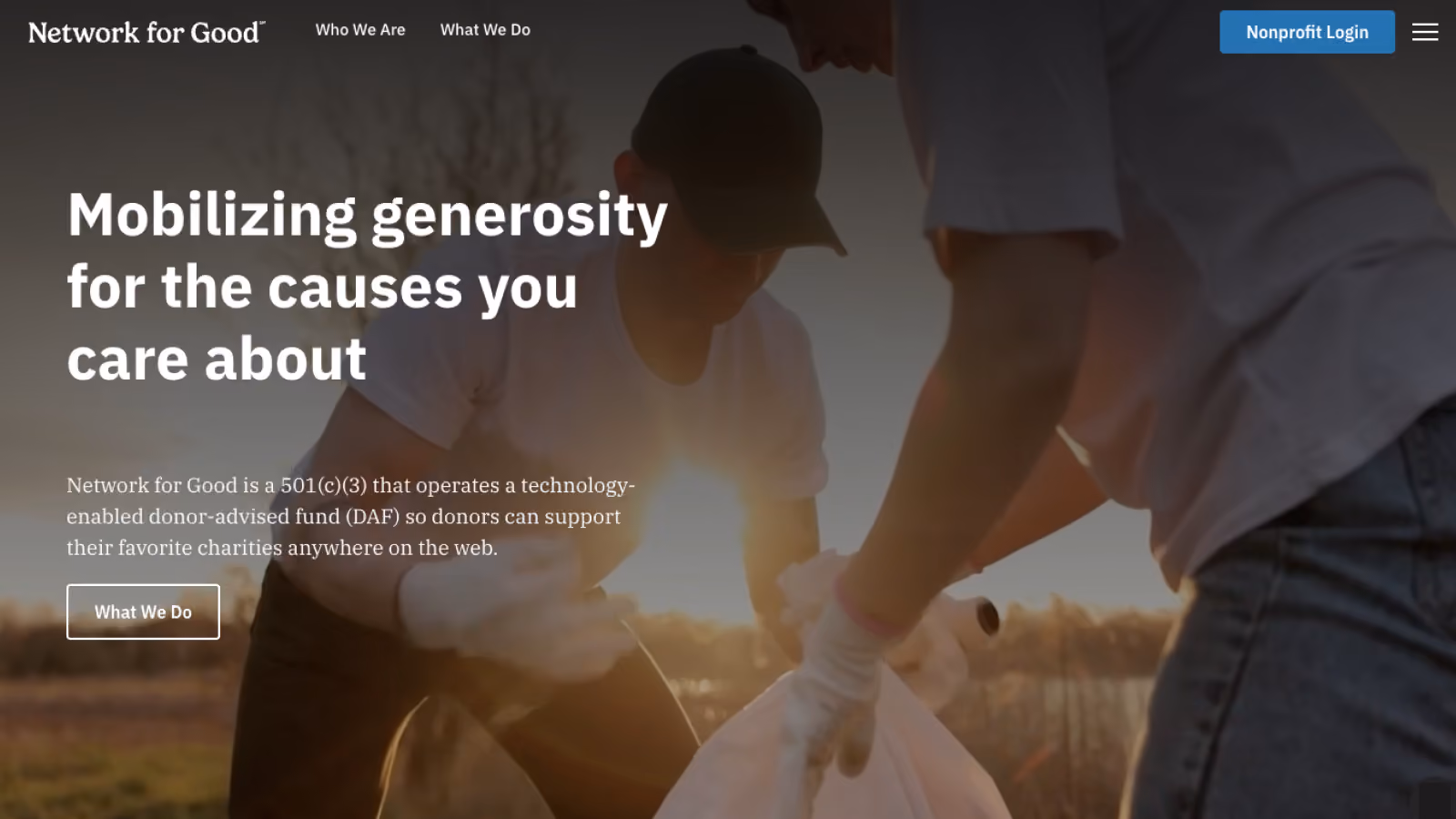 Two people wearing gloves picking up trash outdoors at sunset to support community causes.