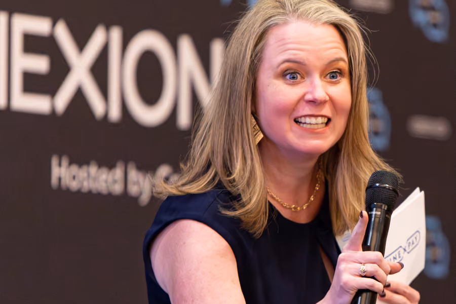 Smiling woman with blond hair speaks into microphone at a Connexions event.