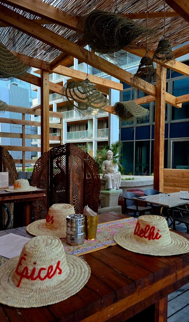 Terrasse ombragée du Bombay Talkies à Grenoble, pergola en bois, paravents indiens et chapeaux de paille brodés