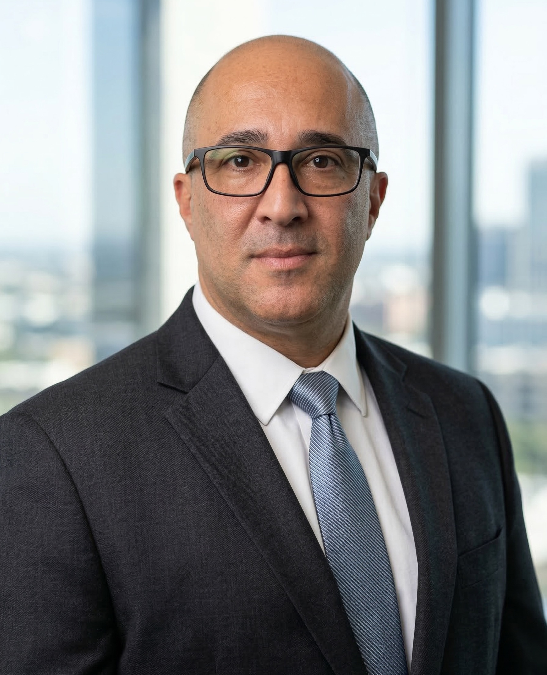 A man with glasses poses for his headshot.