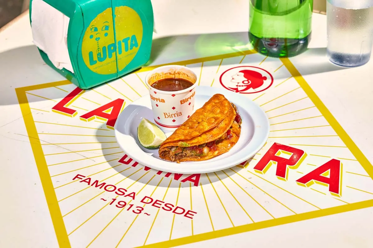 Beef birria taco with melted cheese, served with consomé for dipping