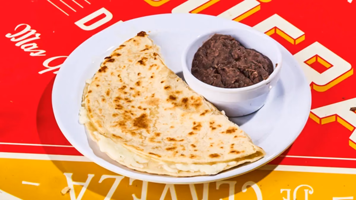 Freshly made flour tortilla filled with melted Oaxaca cheese, served with a side of refried black beans.