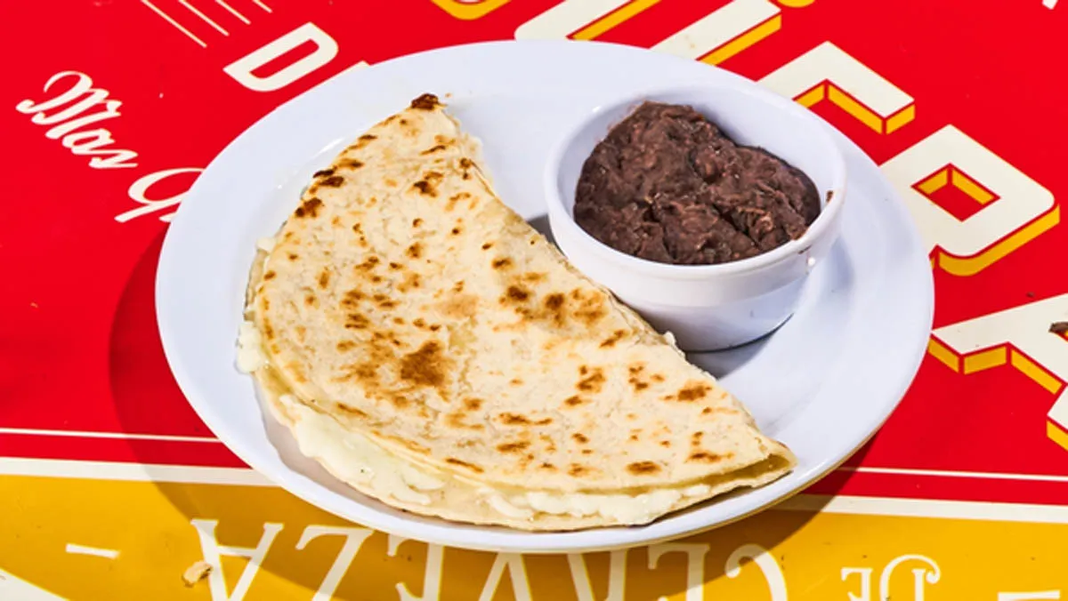 Freshly made flour tortilla filled with melted Oaxaca cheese, served with a side of refried black beans.