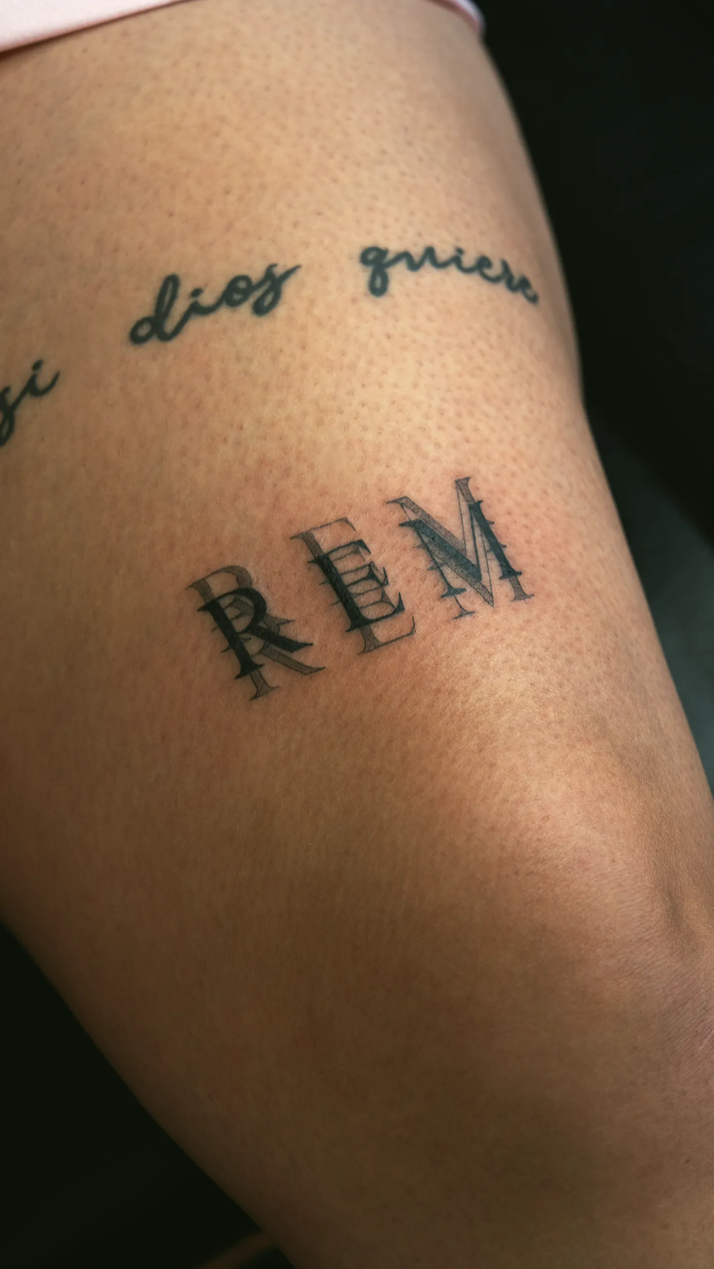 Script reading "REM" tattooed on the leg