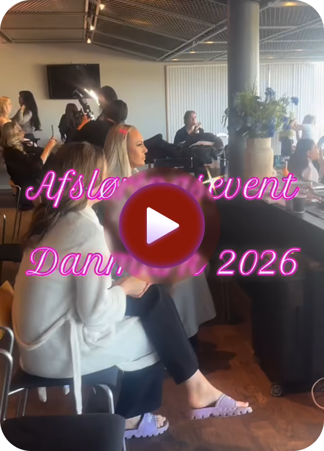 People seated and engaged at an indoor event with a play button overlay and neon text in Danish.