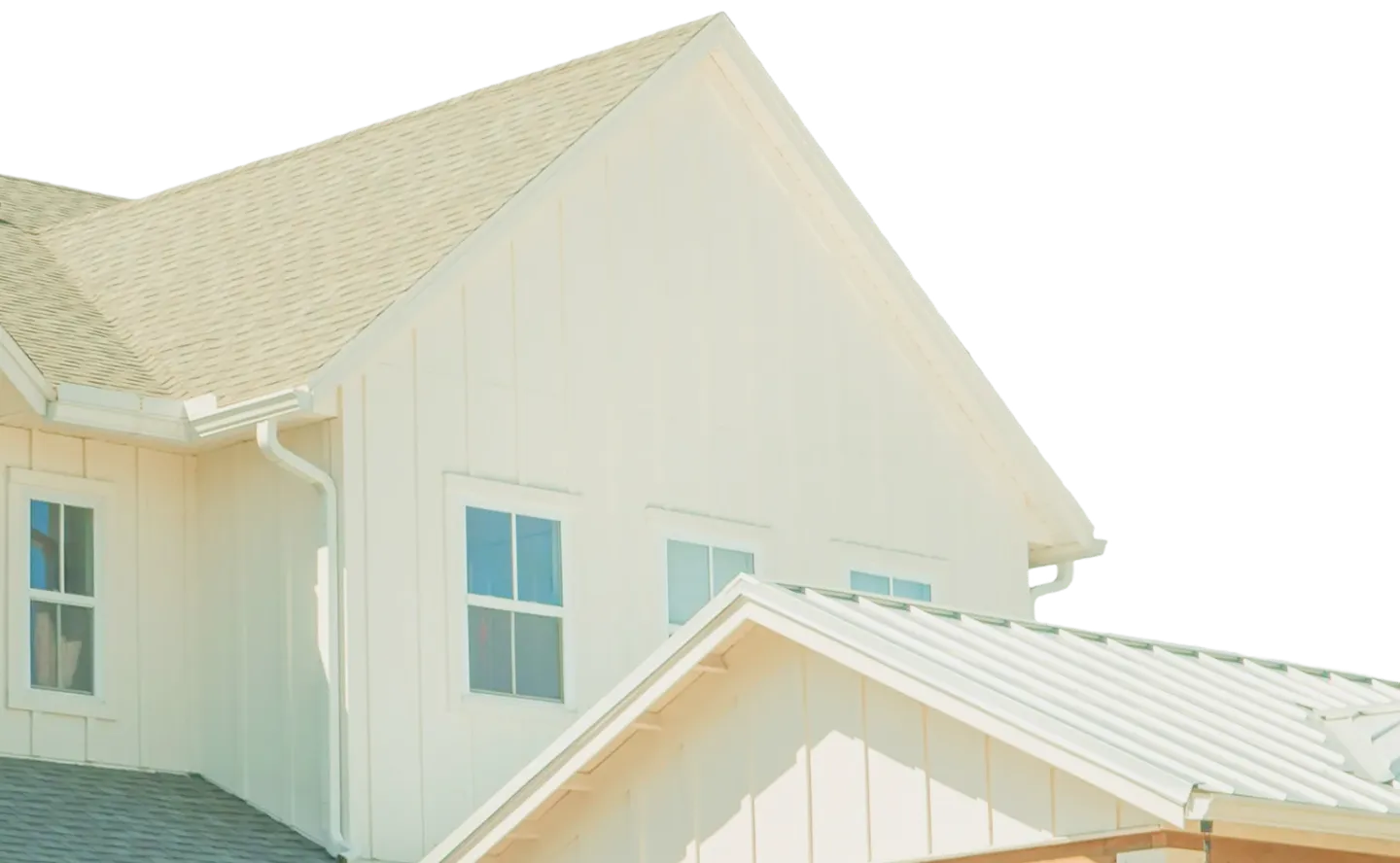 Upper section of a beige house showing windows, roof, and gutter system in daylight.