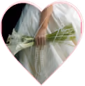 Hands holding a wrapped bouquet of white flowers against a fabric backdrop, framed in a heart shape.