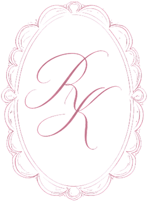 Monogram "RK" in elegant script inside an ornate oval frame in pink.