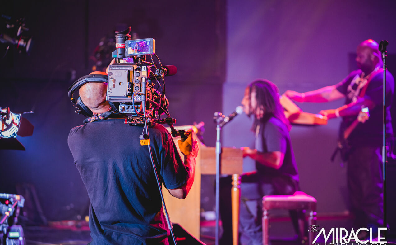 A camera operator shooting a band from the stage floor
