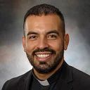 Father Juan Mendez smiling in clerical collar headshot photo