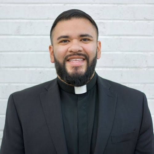 Rev. Ignacio Olvera smiling in clerical collar and black suit