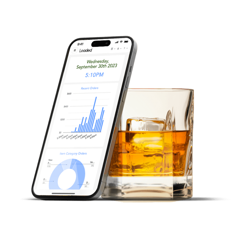 Smartphone displaying sales data with bar and pie charts leaning against a glass of whiskey with ice.