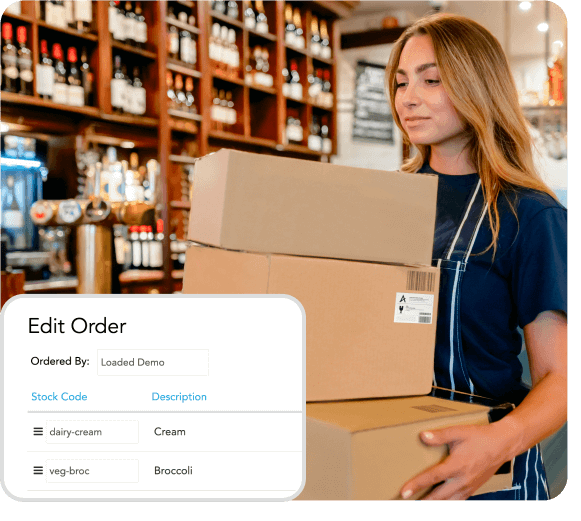 Woman in apron carrying stacked cardboard boxes in a store with wine bottles on shelves, with an overlay of an order editing interface showing items Cream and Broccoli.