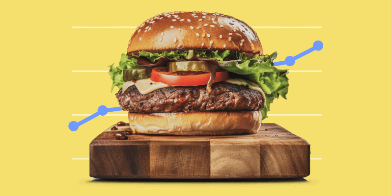 Juicy cheeseburger with lettuce, tomato, pickles, and bacon on a sesame seed bun, placed on a wooden cutting board with a stylized blue upward trend line graph in the background.
