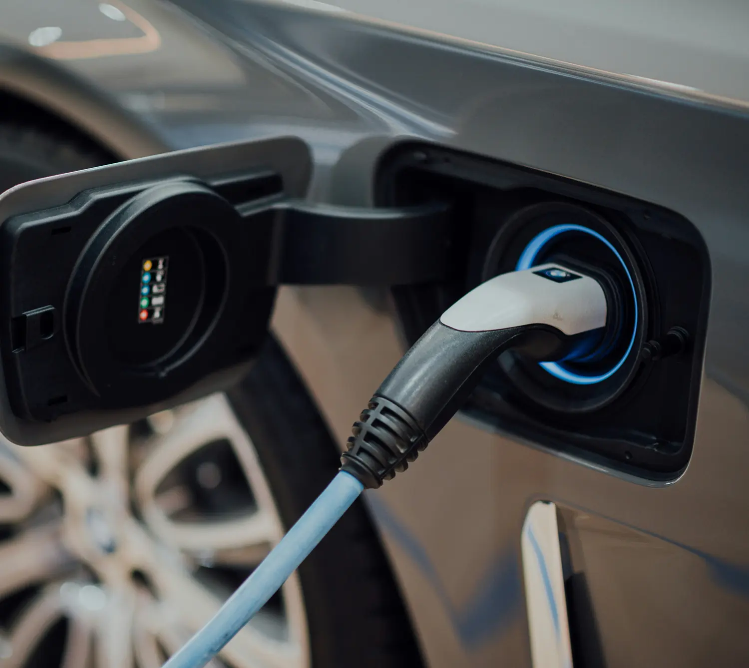 Close-up of an electric car charging port with a charging cable plugged in.