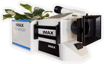 White IMAX projector-shaped planter with green plants growing from the back.