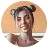 Smiling young woman with dark hair styled in two buns and wearing a light gray sleeveless top, posing against a light background.