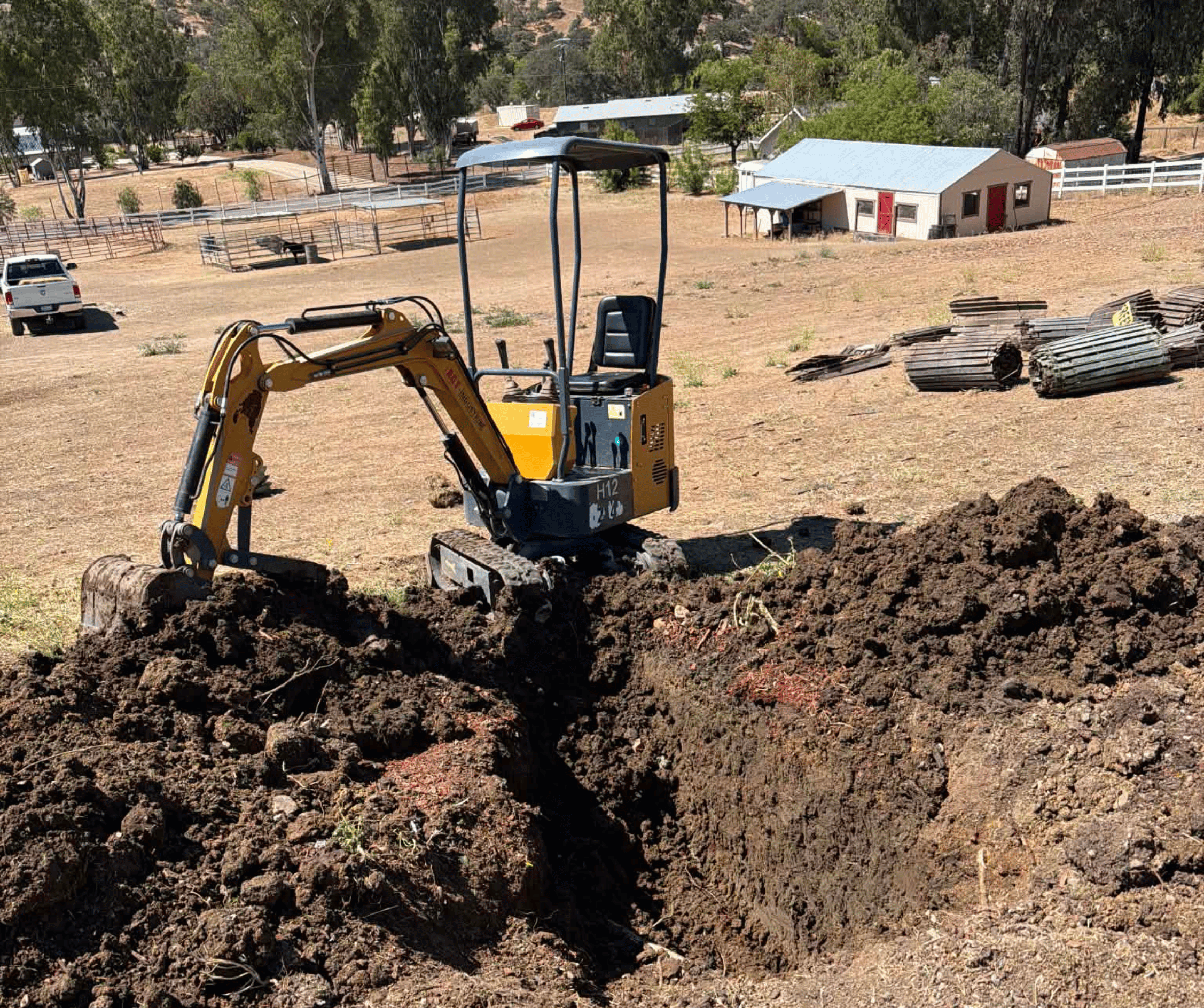 Excavator with red and gray body digging on a construction site under a clear sky.