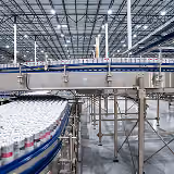 Production line with numerous cans moving along a conveyor belt in a factory setting.