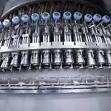 Row of industrial gauges and valves mounted on a metal panel in a factory setting.