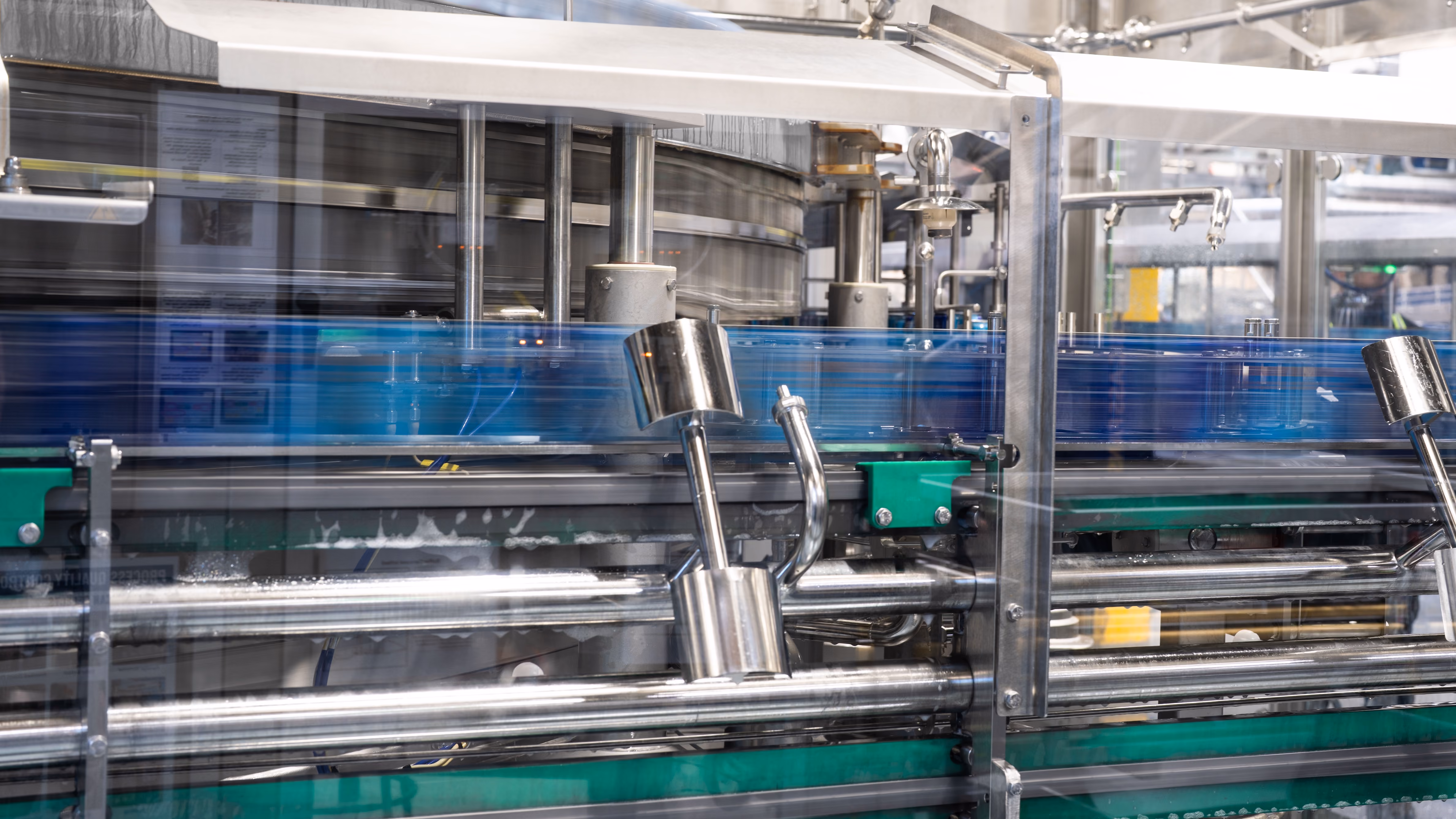 Industrial machine filling or capping blue plastic bottles in a production line.