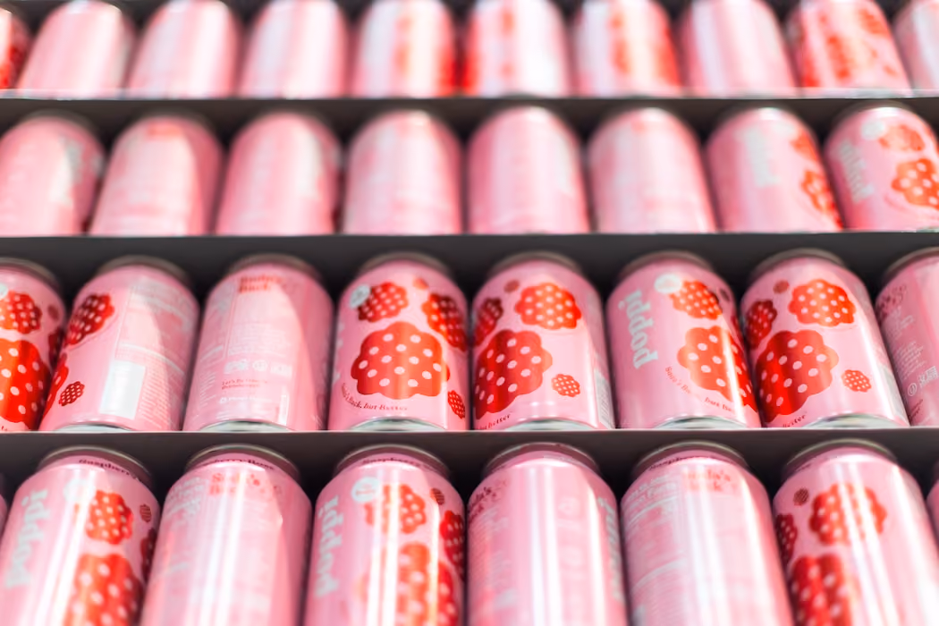 Rows of pink cans with red polka dot designs stacked on shelves in a store.