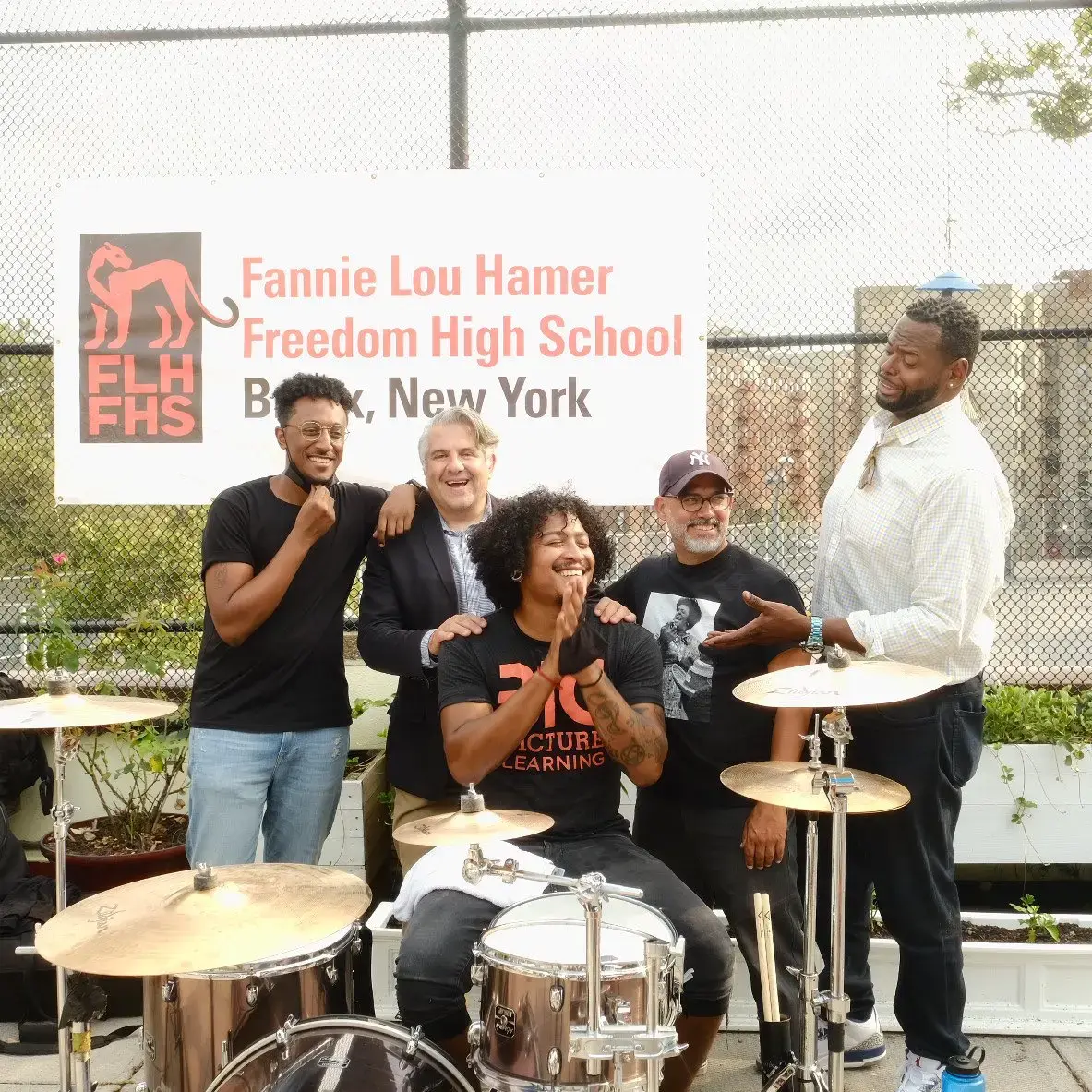Group posing with drums outside Fannie Lou Hamer Freedom High School