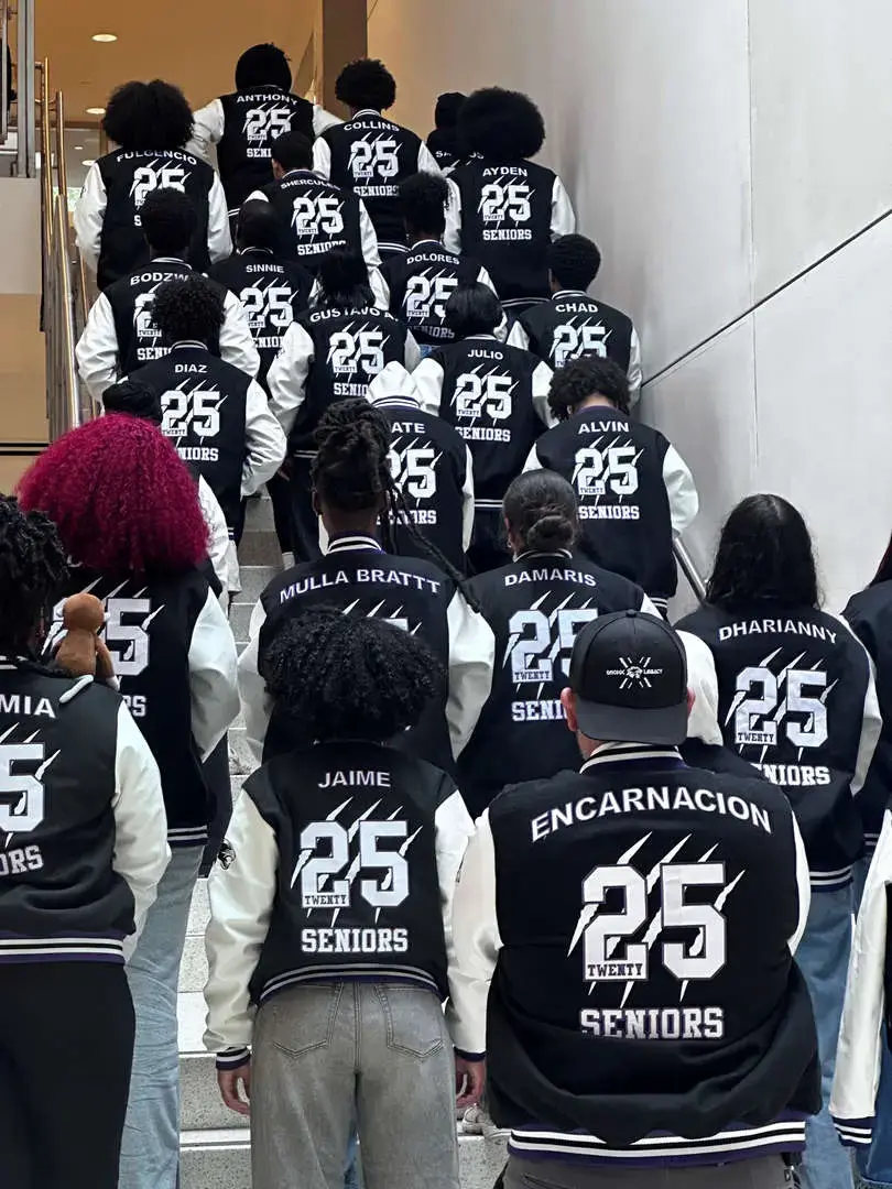 Class of 2025 seniors wearing personalized letterman jackets ascending stairs