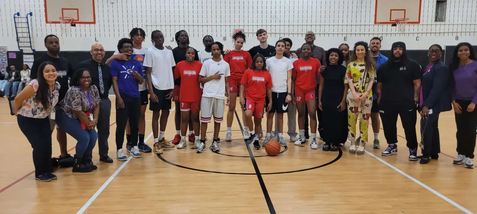 Students and staff posing together on school gymnasium basketball court