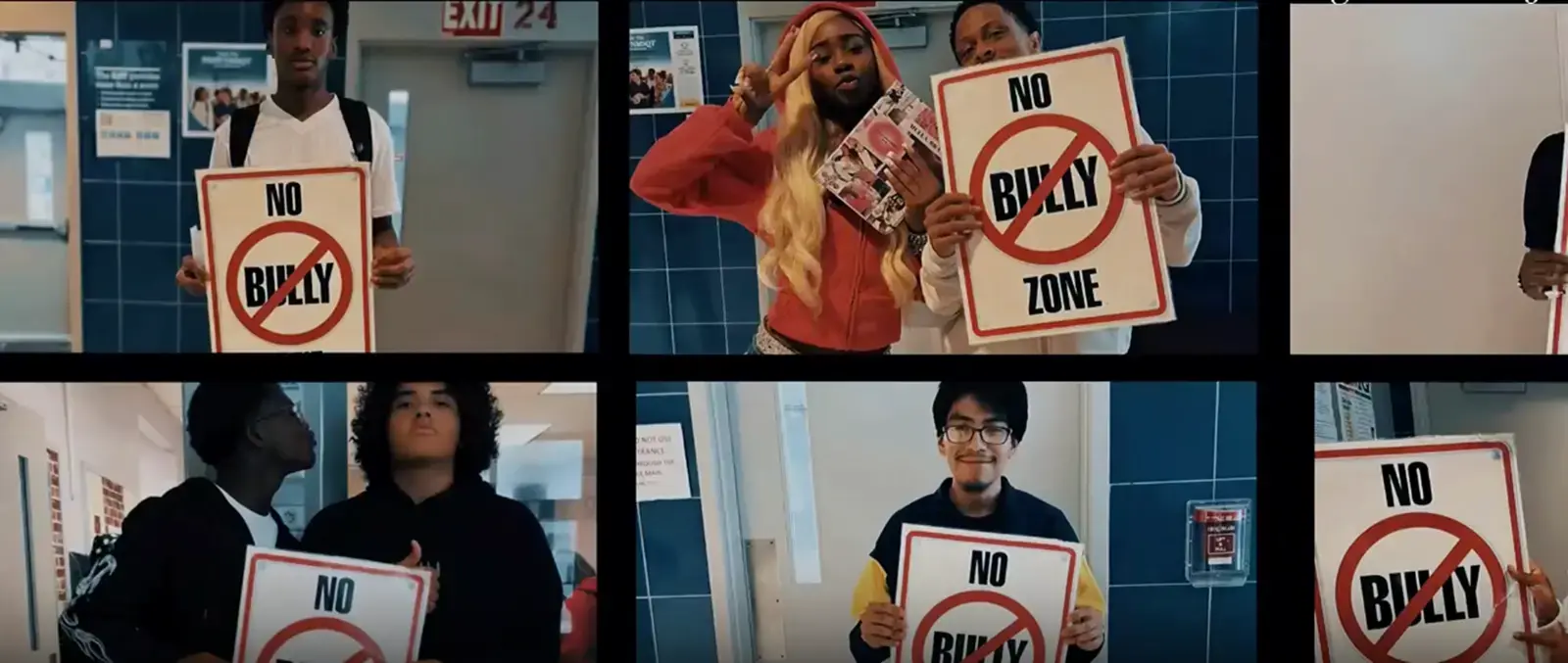 Students holding No Bully Zone signs in school hallway