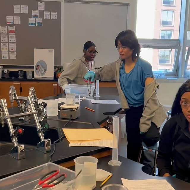 Teacher guides students during a high school science lab experiment